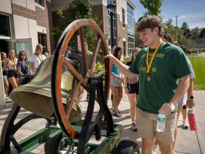 Male student rings the victory bell outside the fitness center