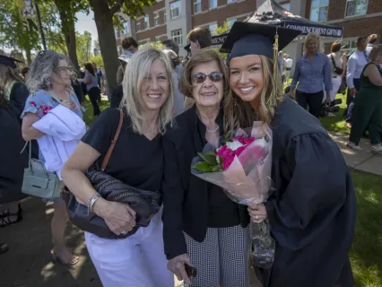 Graduate holding a bouquet of flowers with family members