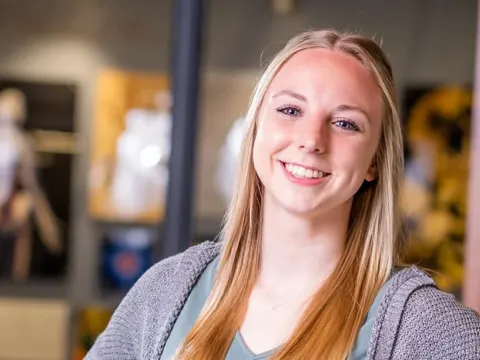 Image of female student standing in front of an anatomy lab
