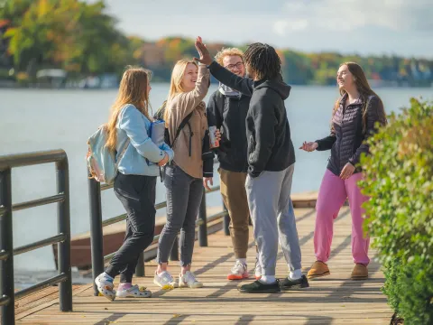 Students gather and talk on the docks with the river in the background