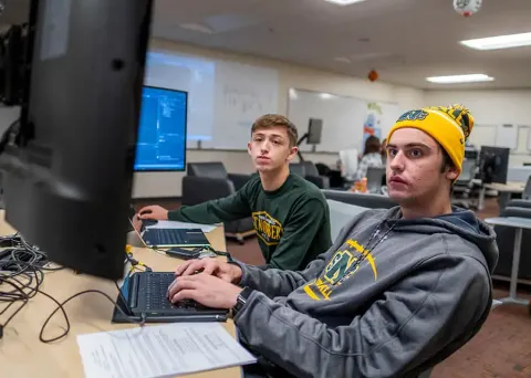Two students working on a project on computers