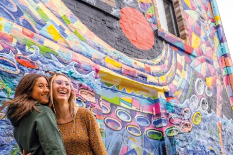 Two girls in front of a mural