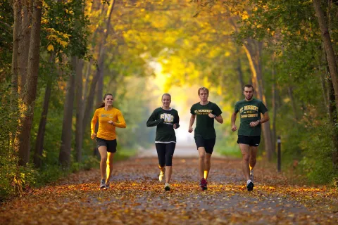 Four SNC students running on the Fox River Trail