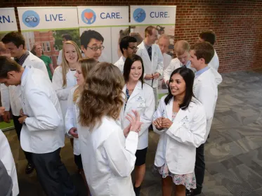 Students in white coats talking to each other