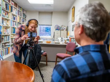 Student adjusting a camera while filming someone for a video